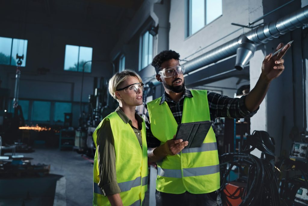 Portrait of industrial inspectors doing a general check up indoors at metal workshop